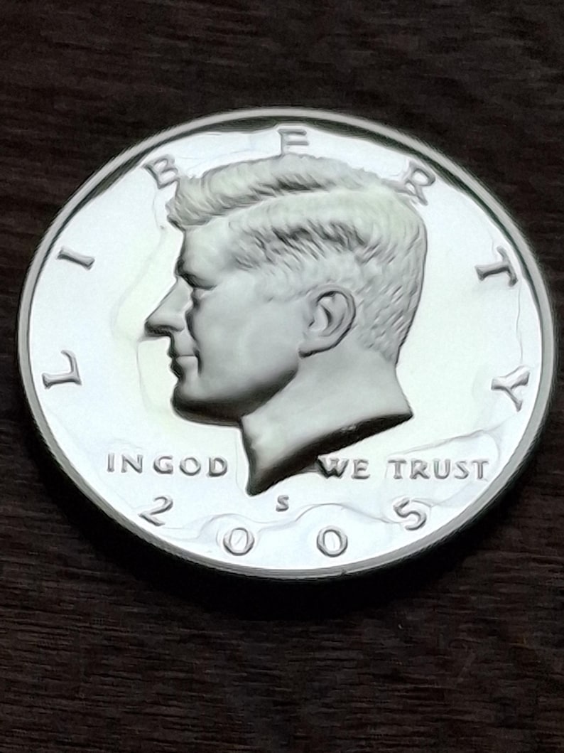 K&ouml;nnte beinhalten: Eine silberne 2005 Kennedy Half-Dollar-M&uuml;nze. Die M&uuml;nze zeigt ein Profil von John F. Kennedy und die Inschriften "LIBERTY", "IN GOD WE TRUST" und "UNITED STATES OF AMERICA".