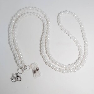 May include: White pearl glasses chain with silver clasps and clear silicone loops.