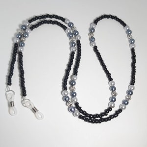 May include: Black and silver beaded eyeglass chain with silver accents. The chain has two clear plastic clasps for attaching to glasses.