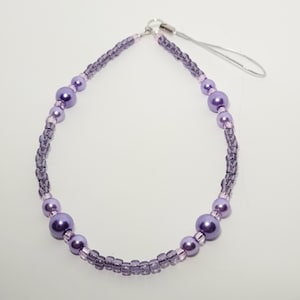 May include: A purple beaded phone charm with a silver clip and a purple and pink beaded strap.