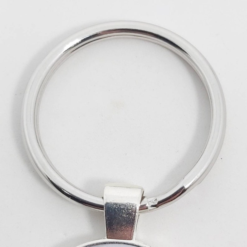 May include: Silver key ring with a round metal loop. The loop is smooth and shiny.