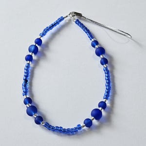 May include: A blue beaded phone charm with a silver clasp and a silver chain.