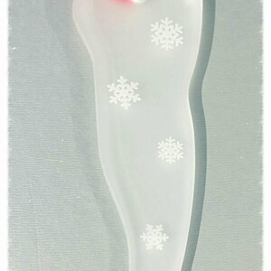 May include: White frosted glass Christmas ornament shaped like a stocking with a red ribbon and white snowflakes.