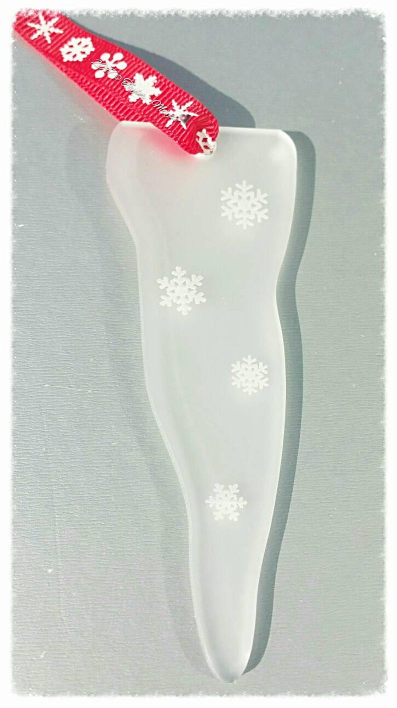 May include: White frosted glass Christmas ornament shaped like a stocking with a red ribbon and white snowflakes.