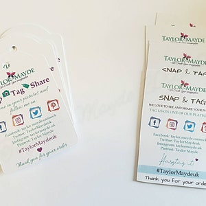 Peut inclure: Une pile d'étiquettes blanches avec un logo papillon et le texte "Taylor Mayde" et "Snap & Tag". Les étiquettes comprennent des icônes de médias sociaux et des instructions pour taguer la société sur les médias sociaux. Le texte "Merci pour votre commande" est également inclus.