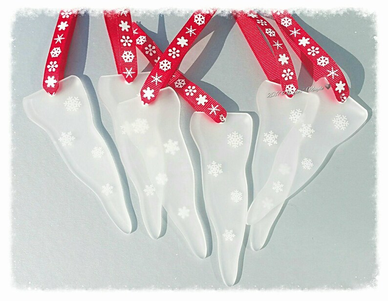 May include: Five white frosted glass icicle ornaments with snowflake designs, each with a red ribbon with white snowflake print.