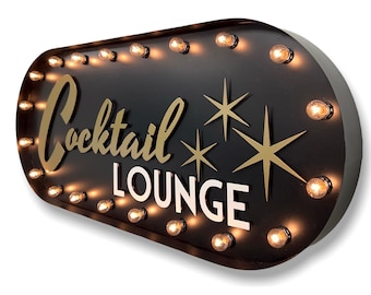 May include: Black metal sign with gold lettering that reads "Cocktail Lounge" and has white stars. The sign has a row of light bulbs around the perimeter.