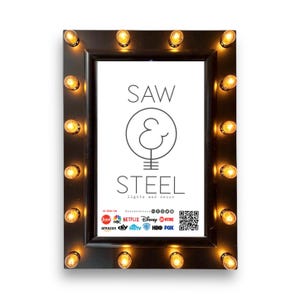 Puede incluir: Marco rectangular negro con bombillas de luz cálida alrededor del perímetro. El marco tiene el texto "SAW & STEEL lights and decor" en el centro. Logotipos de varios medios de comunicación en la parte inferior.