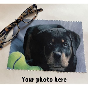 May include: Eyeglasses with a floral pattern rest on a microfiber cloth featuring a Rottweiler puppy with a tennis ball. The cloth has the text "Your photo here" at the bottom.