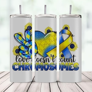 May include: Three white stainless steel tumblers with a blue and yellow design. The design features a peace sign, a heart with jigsaw pieces, and a yellow ribbon. The text "love doesn't count chromosomes" is printed on the tumblers.