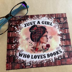 May include: A red and white microfiber cleaning cloth with a design of a woman standing in front of a bookshelf. The text "Just a girl who loves books" is printed on the cloth.