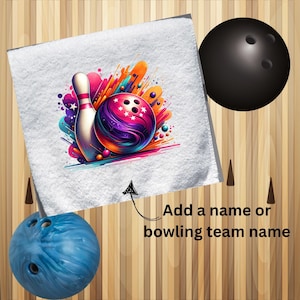 Puede incluir: Toalla blanca con un diseño colorido de bola y bolos de bolos. El diseño presenta una bola de bolos con colores morado, naranja y azul y un pin blanco. El texto "Añadir un nombre o un nombre de equipo de bolos" está debajo del diseño.
