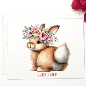 May include: A cute brown bunny wearing a flower crown with pink, white, and blue flowers. The bunny is sitting on a white background with the text "Happy Easter" below it.