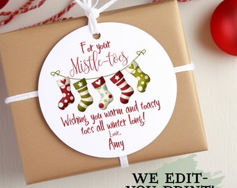 May include: A white round gift tag with a red and green illustration of stockings hanging from a string with the text "For your Mistle-toes Wishing you warm and toasty toes all winter long! Love, Amy"