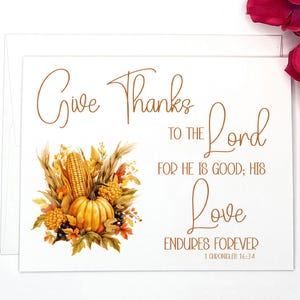May include: A Thanksgiving card with a fall harvest theme. The card features a watercolor illustration of a pumpkin, corn, and fall leaves. The text on the card reads "Give Thanks to the Lord for He is Good; His Love Endures Forever 1 Chronicles 16:34".