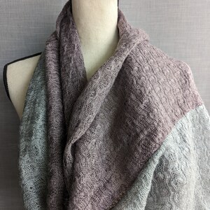 K&ouml;nnte beinhalten: Ein weicher, gestrickter Schal in Graut&ouml;nen und Blau. Der Schal ist &uuml;ber die Schultern einer Schaufensterpuppe gelegt und aus einem zarten, offen gewebten Stoff gefertigt.