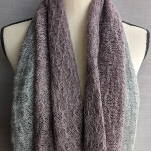 K&ouml;nnte beinhalten: Ein weicher, gestrickter Schal in zwei Graut&ouml;nen. Der Schal ist in der H&auml;lfte gefaltet und &uuml;ber den Hals einer Schaufensterpuppe gelegt. Der Schal ist aus einem leichten, atmungsaktiven Stoff gefertigt, der sich perfekt zum Schichten eignet.