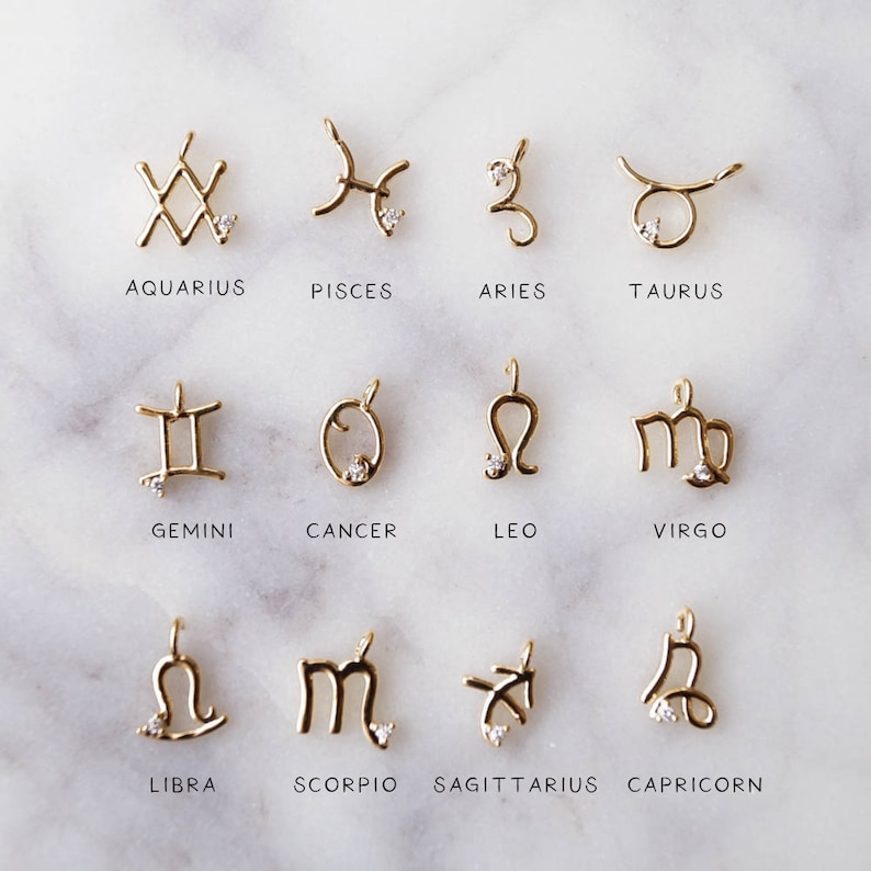 May include: Twelve gold zodiac sign charms with a small diamond accent. The charms are arranged in three rows of four. The signs are Aquarius, Pisces, Aries, Taurus, Gemini, Cancer, Leo, Virgo, Libra, Scorpio, Sagittarius, and Capricorn.