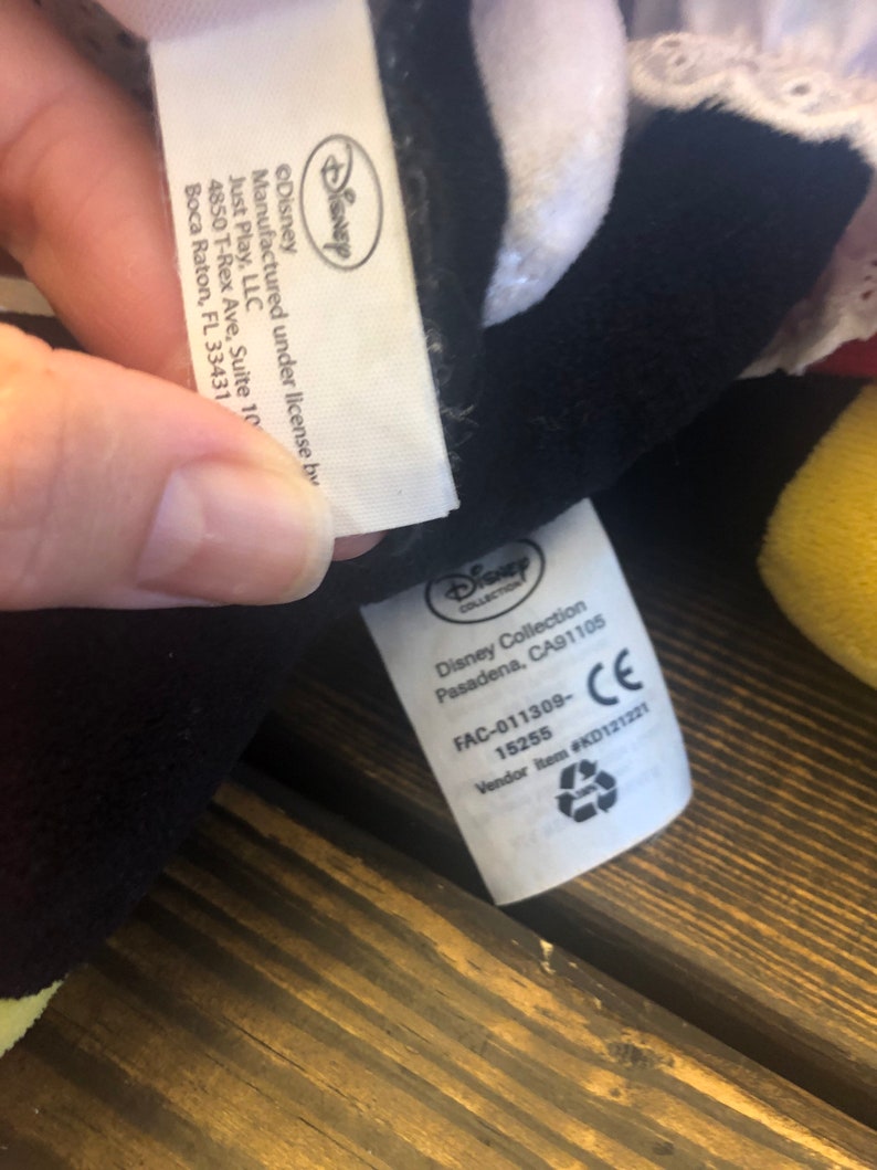 May include: White and black plush toy with a white tag that reads "Disney Collection Pasadena, CA91105 FAC-011309-15255 Vendor Item #KD121221 CE".