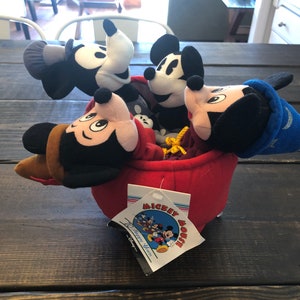 Peut inclure: Une maison en peluche rouge Mickey Mouse avec quatre figurines en peluche Mickey Mouse &agrave; l'int&eacute;rieur. La maison a une &eacute;tiquette qui dit "Mickey Mouse 70 Happy Years".