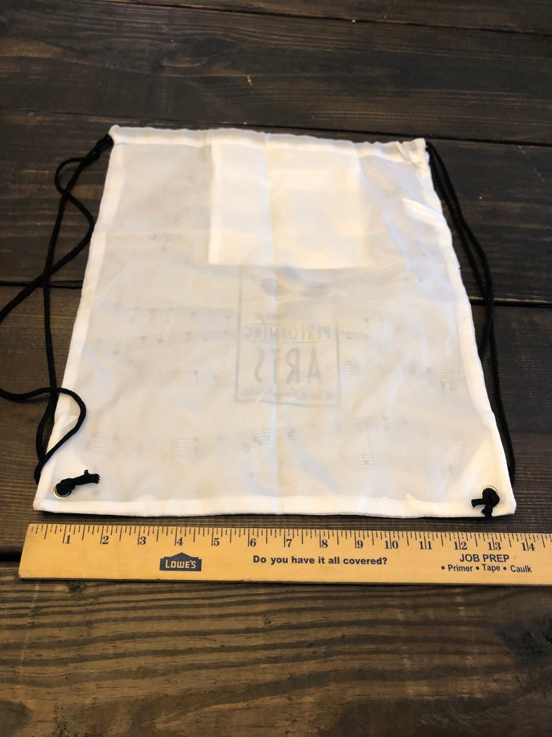 May include: White drawstring bag with black drawstrings and a white logo that says "Remarkable Arts" printed on the front.