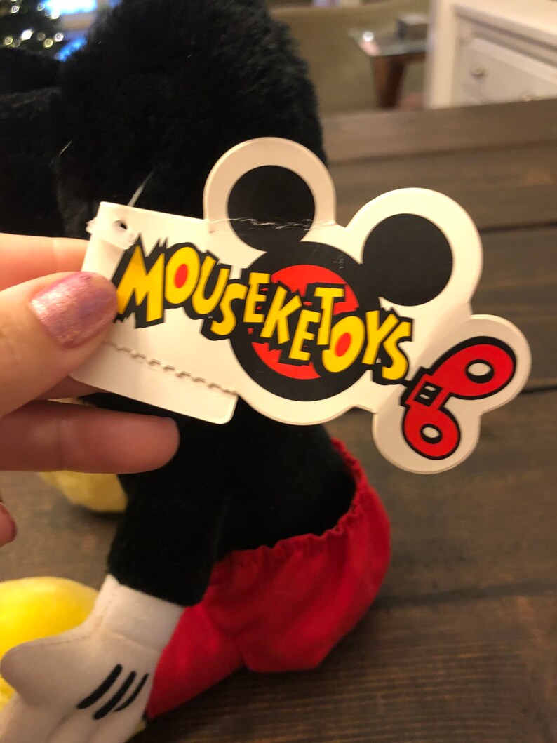May include: Black and red plush Mickey Mouse toy with a white tag that says "Mouseketoys" with a red and yellow Mickey Mouse head and a red and yellow wind-up key.