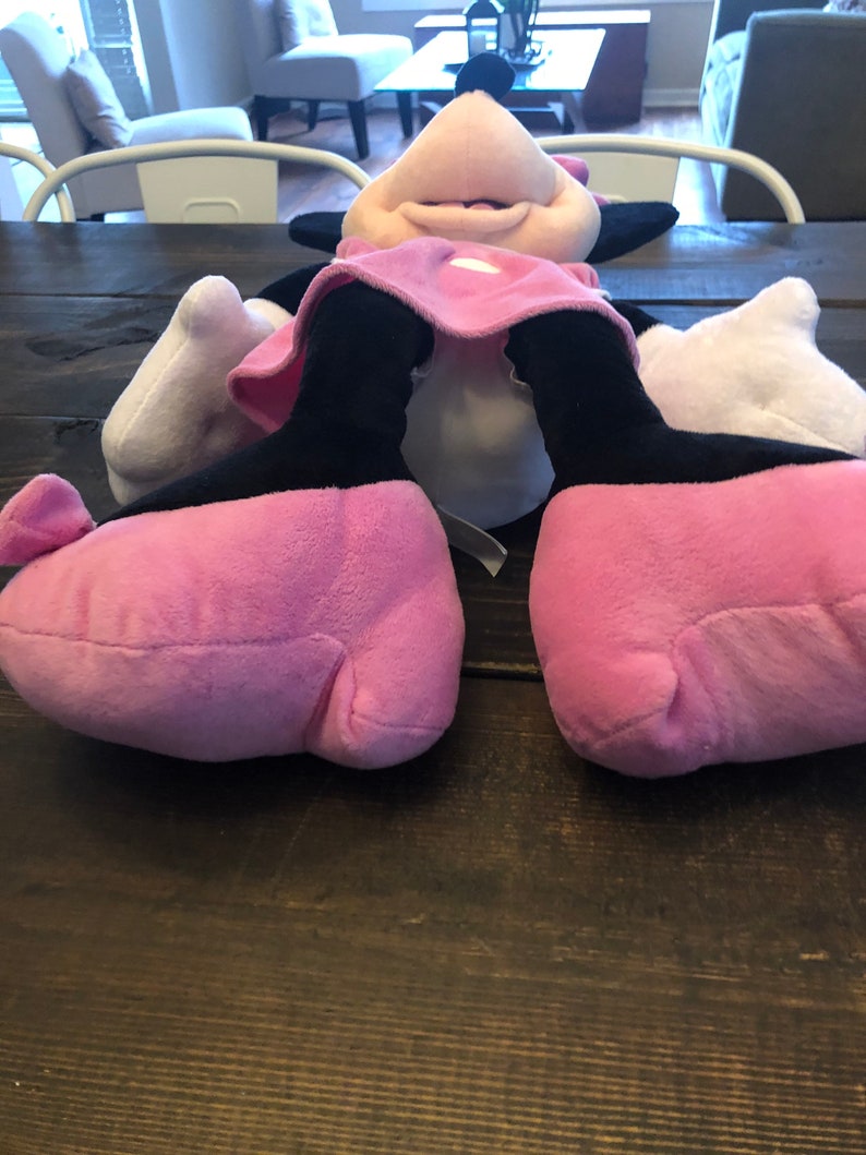 May include: A pink and black plush toy of a cartoon mouse with large feet. The toy is lying on its back with its arms outstretched.