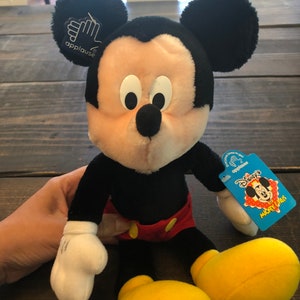 May include: A black and yellow plush Mickey Mouse toy with a red and white shirt and a blue tag that says "Disney's Mickey & Pals".