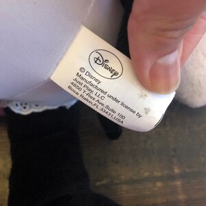 May include: White tag with black text that reads "Disney", "&copy; Disney", "Manufactured under license by Just Play, LLC", "4850 T-Rex Ave, Suite 100", "Boca Raton, FL 33431, USA".