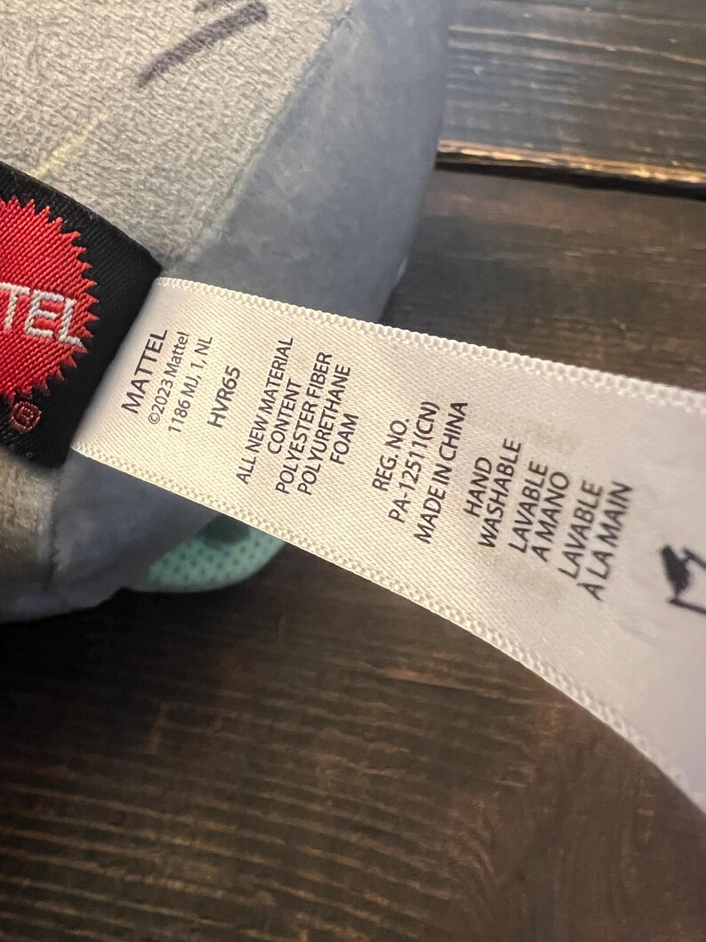 Pode incluir: Uma caneca de cer&acirc;mica branca com uma al&ccedil;a preta e o texto "But First, Coffee" em preto, com uma fonte manuscrita. A caneca est&aacute; sobre uma superf&iacute;cie branca.
