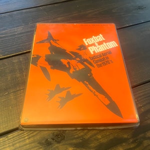 May include: A red box with a black and white illustration of a fighter jet. The text on the box reads "Foxbat & Phantom Tactical Aerial Combat in the 1970's".