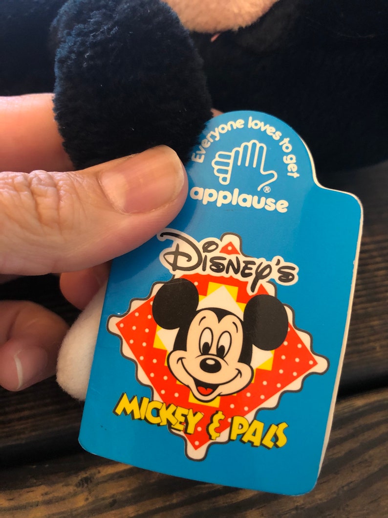 May include: A blue and white tag with the text "Disney's Mickey & Pals" and a cartoon image of Mickey Mouse. The tag also has the text "Everyone loves to get applause" with a hand clapping.