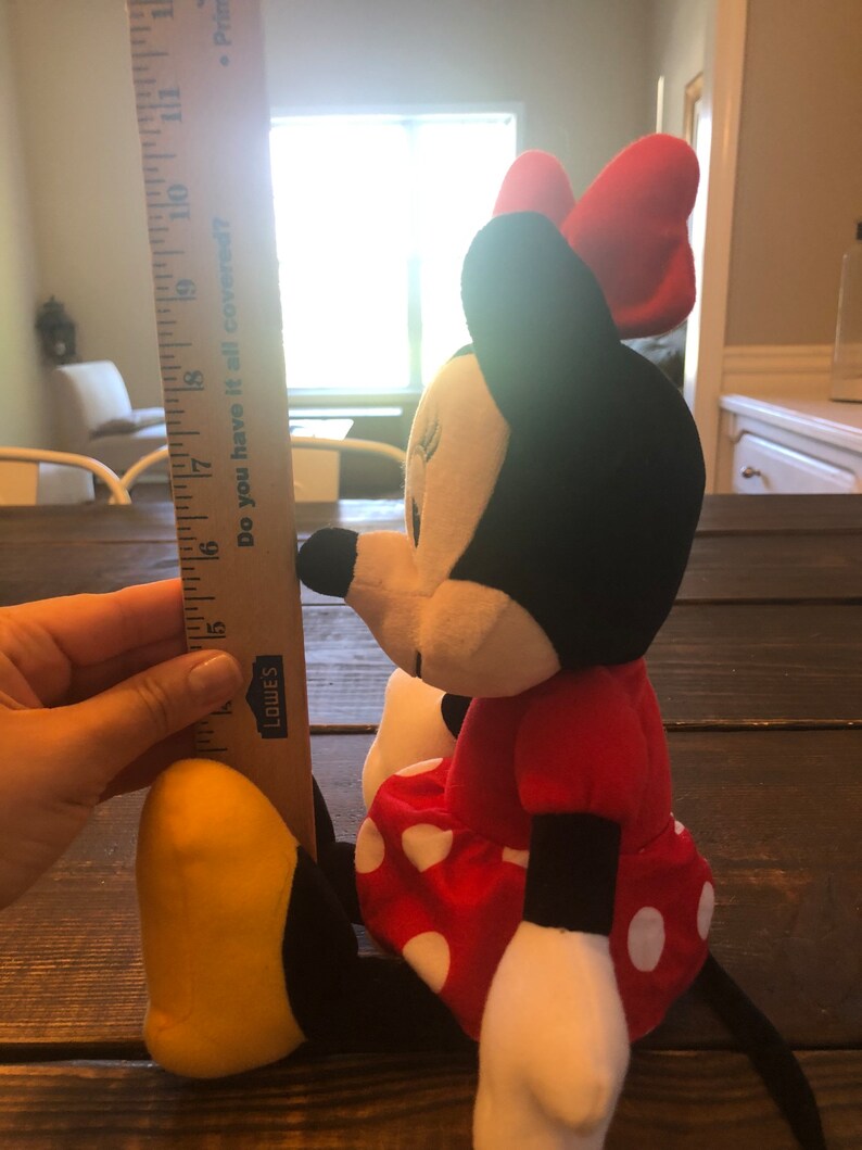 May include: A red and black plush toy of Minnie Mouse, wearing a red dress with white polka dots and a red bow. The toy is approximately 15 inches tall.