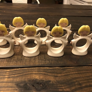 Puede incluir: Conjunto de ocho anillos de servilleta de cer&aacute;mica blanca en forma de &aacute;ngel con cabello y alas amarillas. Los anillos est&aacute;n dise&ntilde;ados para sujetar las servilletas en su lugar.