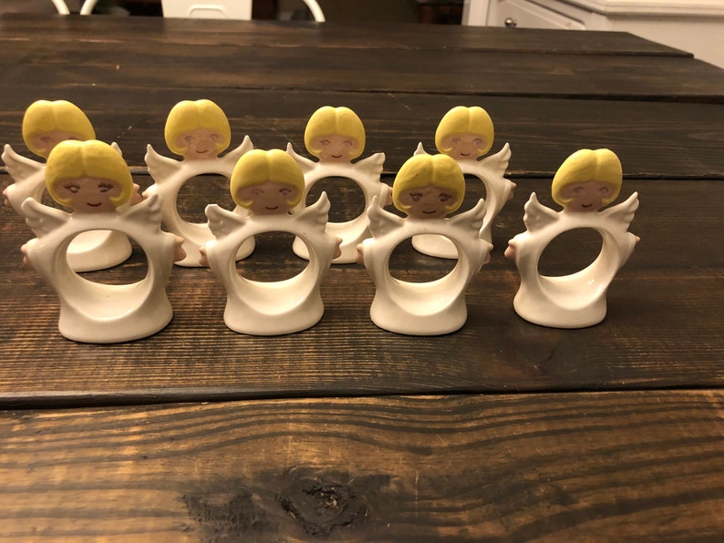Puede incluir: Conjunto de ocho anillos de servilleta de cer&aacute;mica blanca en forma de &aacute;ngel con cabello y alas amarillas. Los anillos est&aacute;n dise&ntilde;ados para sujetar las servilletas en su lugar.