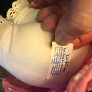 May include: Pink polka dot Minnie Mouse plush toy with a white lace trim and a white tag that reads "WALT DISNEY Pink Polka Dot Minnie 70135 The Walt Disney Company. Manufacture by Playskool, Inc. a subsidiary of Has Inc. All Rights Reserved. Surface Washable Only. All New Materials: 100% Polyester stuffing."
