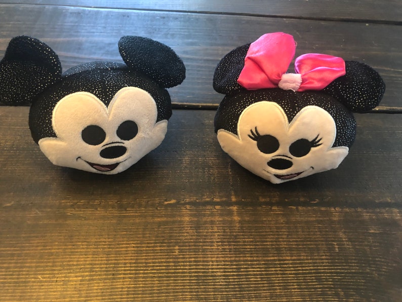 May include: Two plush toys of Mickey Mouse and Minnie Mouse. Mickey Mouse is black with white accents and Minnie Mouse is black with white accents and a pink bow.