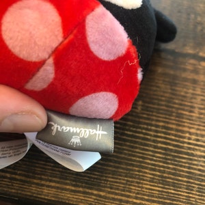 Op de afbeelding: Rood en zwart lieveheersbeestje knuffel met witte stippen. Het speelgoed heeft een Hallmark-label.