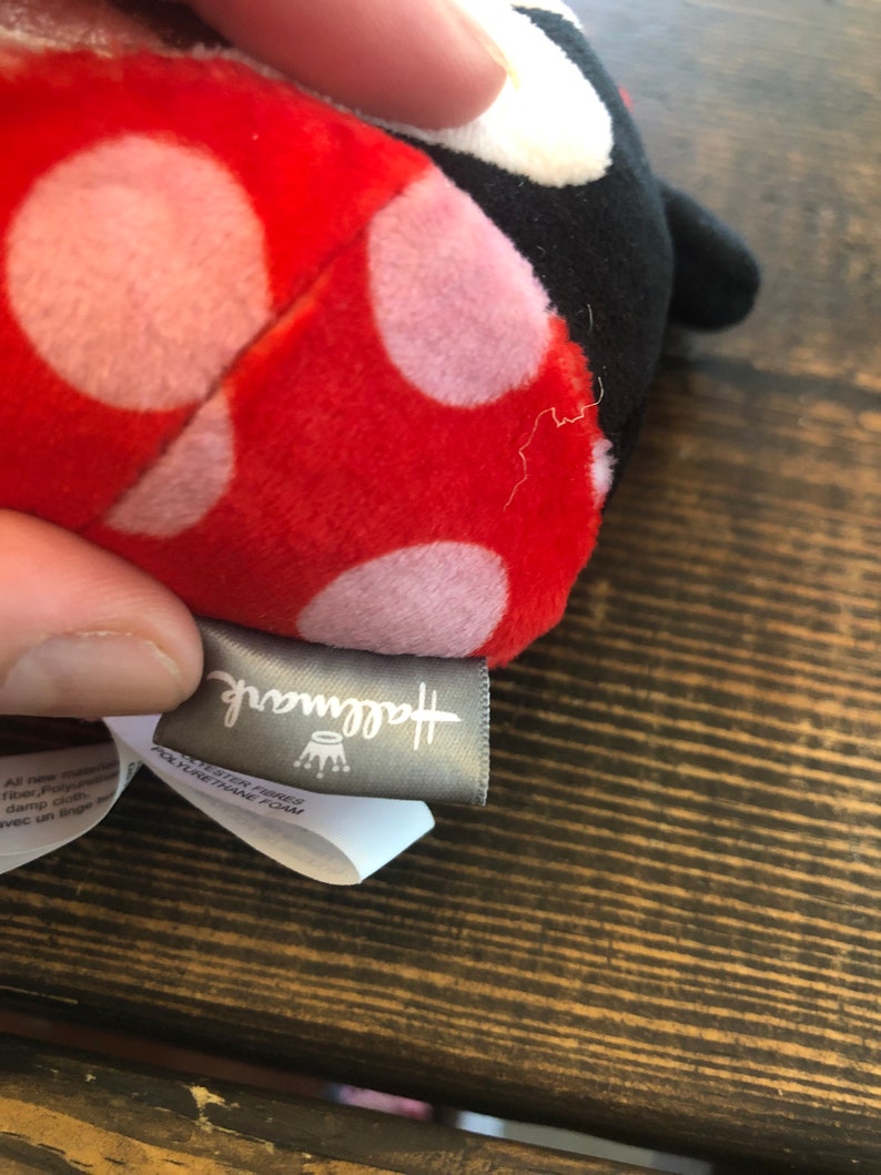 Op de afbeelding: Rood en zwart lieveheersbeestje knuffel met witte stippen. Het speelgoed heeft een Hallmark-label.