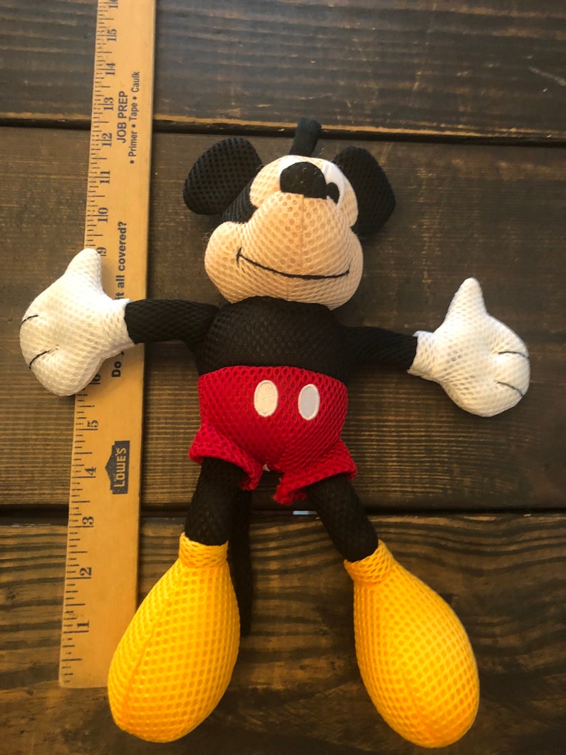 May include: A black and red Mickey Mouse plush toy with yellow mesh shoes. The toy is made of a soft, mesh material and has a friendly expression.
