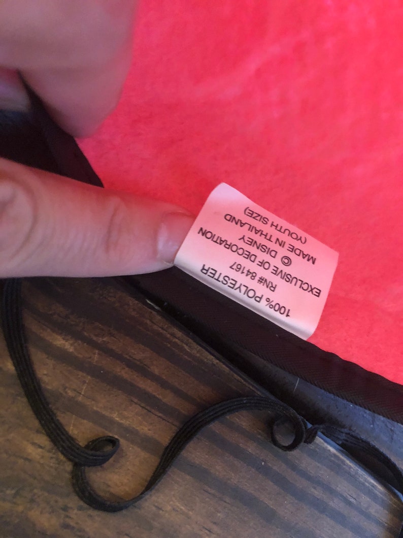 May include: A red polyester youth-sized blanket with a white label that reads "100% Polyester RN# 84167 &copy;DISNEY EXCLUSIVE OF DECORATION MADE IN THAILAND (YOUTH SIZE)"
