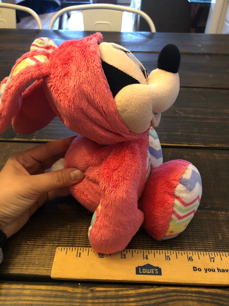 Op de afbeelding: Roze pluche konijn met een kleurrijk paasei-patroon. Het konijn heeft een zwarte neus en grote oren.