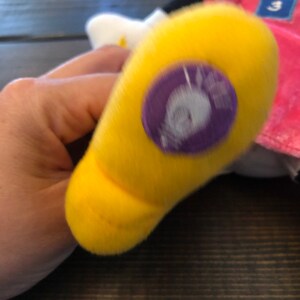 May include: A yellow plush toy foot with a purple and white tag that says "Minnie Mouse".
