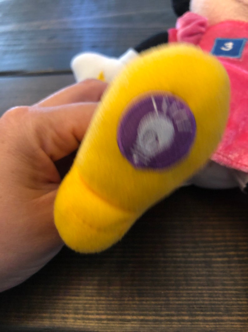 May include: A yellow plush toy foot with a purple and white tag that says "Minnie Mouse".