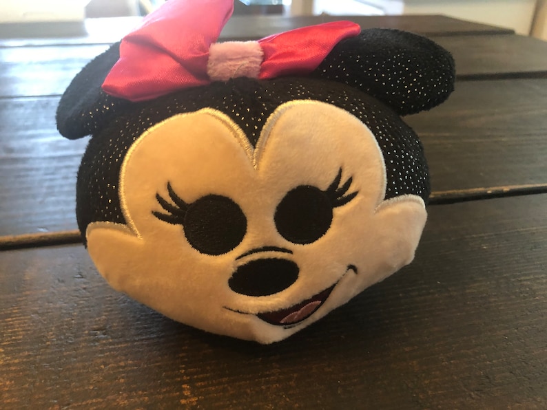 May include: A black and white plush toy with a pink bow. The toy has a sparkly black fabric and a white face with embroidered features.