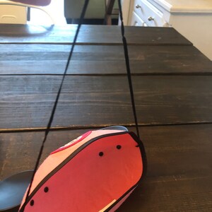 May include: A pink felt Mickey Mouse hat with black trim and a black strap. The hat has a red circle with a white design on the front.