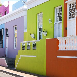 Peut inclure: Une rangée de maisons colorées avec des bordures et des marches blanches. Les maisons sont peintes dans des tons de rose, bleu, violet, vert et orange. Les maisons ont des balustrades blanches et des portes blanches. Les maisons sont situées dans une rue avec un trottoir.