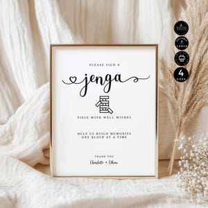 Puede incluir: Un letrero enmarcado con borde dorado y fondo blanco. El letrero dice "Please Sign a Jenga" en una escritura elegante, con una ilustración de bloques de Jenga. También dice "Piece with Well Wishes" y "Help us build memories one block at a time." Firmado por Charlotte y Ethan.
