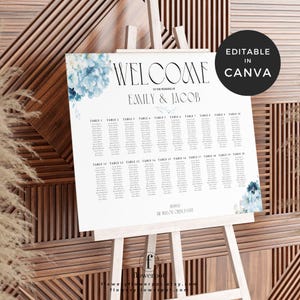 May include: A white wedding seating chart on an easel, featuring the names of guests organized by table number. The chart includes the names "Emily & Jacob" and is decorated with blue floral accents. The words "WELCOME" and "EDITABLE IN CANVA" are also visible.