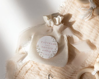 Könnte beinhalten: Ein kleiner weißer Jutesack mit einem runden Aufkleber. Der Aufkleber hat ein Blumenmuster und den Text "FATIMAH AND YOUSUF wedding 21.10.23".
